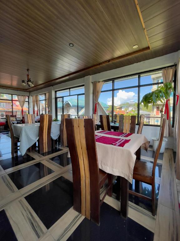 a dining room with a table and chairs and windows at Andrew & Mary's Lodging House in Sagada