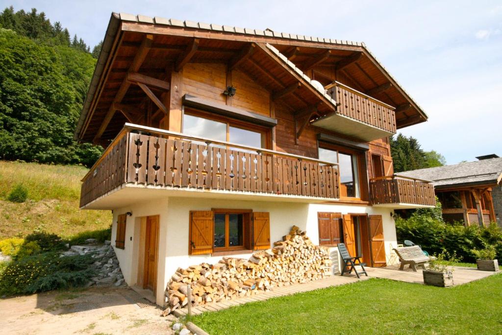 une maison en rondins avec un tas de bois de chauffage sur le sol dans l'établissement Chalet The Loft, aux Gets
