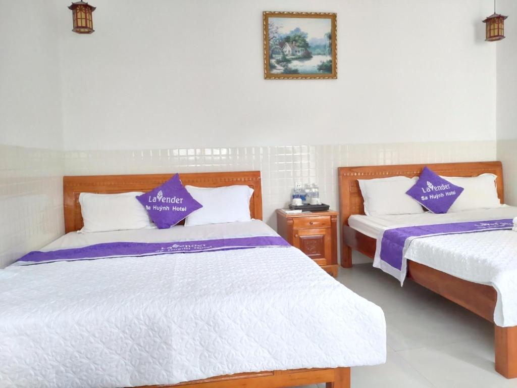 2 Betten in einem Zimmer mit lila und weißen Laken in der Unterkunft Lavender Sa Huỳnh Hotel Quốc Lộ 1A in La Vân (2)