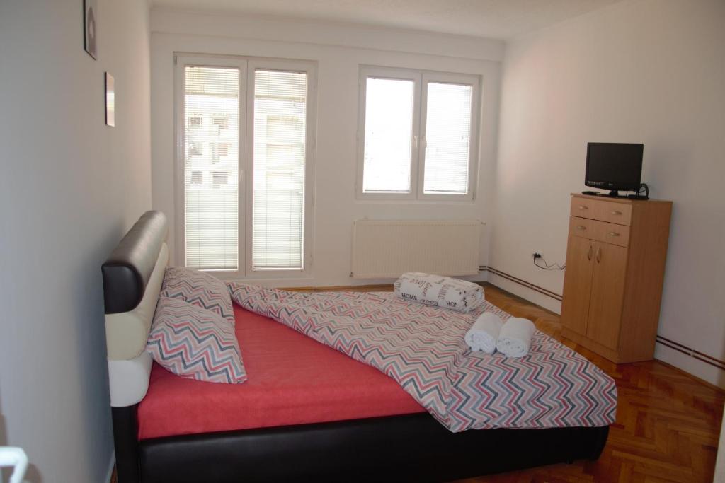 een slaapkamer met een bed met een rode deken bij Goodholiday Apartmens Šabac in Šabac