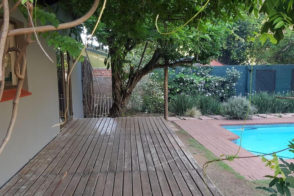a wooden walkway leading to a pool in a yard at Plumb cottage, Greenside in Johannesburg