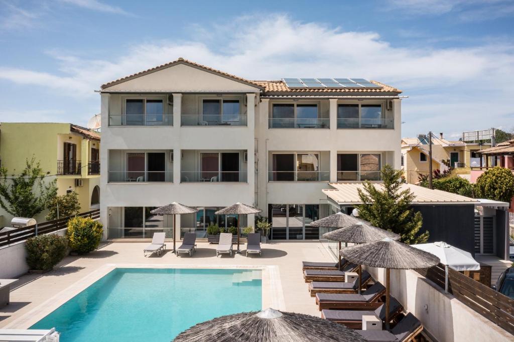 a building with a swimming pool and chairs and umbrellas at Delight Corfu Apart Hotel, Sidari in Sidari