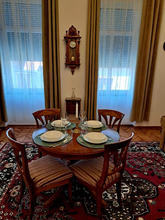 a dining room table with chairs and a clock on the wall at Weisz Castle style Apartment-City Center- Free Private Parking in Carei