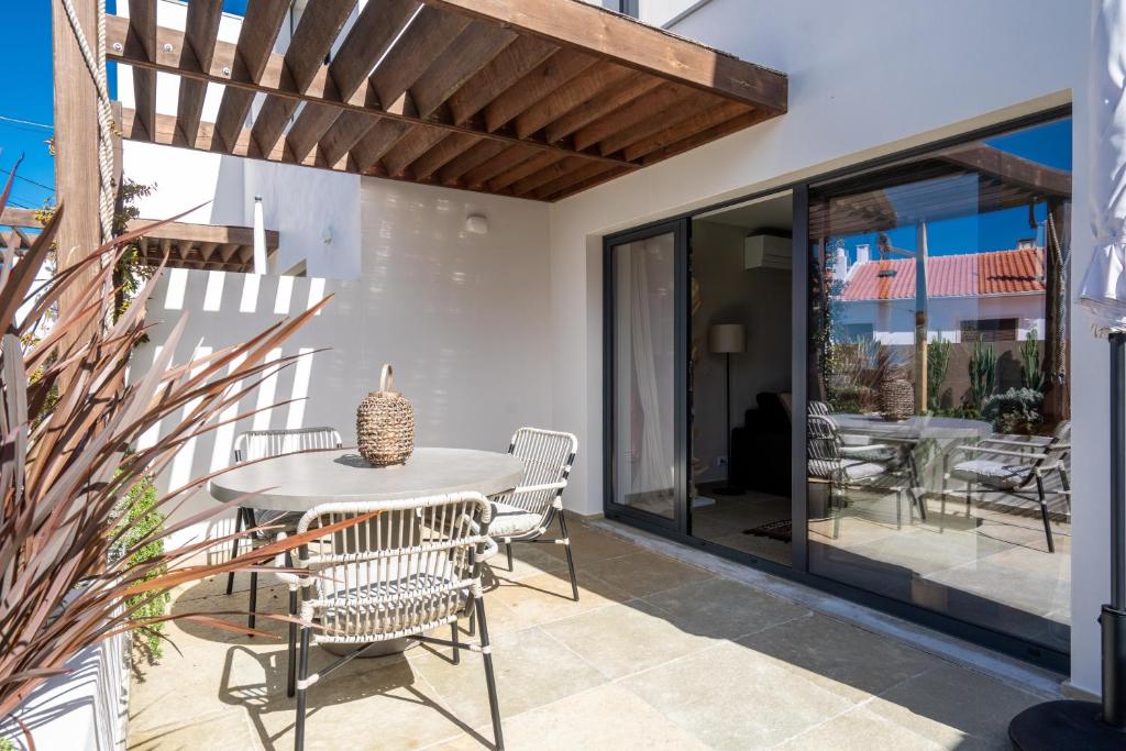 a patio with a table and chairs and sliding glass doors at Casa da Ursa in Colares
