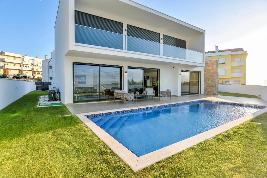 a house with a swimming pool in front of it at Moradia Sussurros do Mar in Nazaré