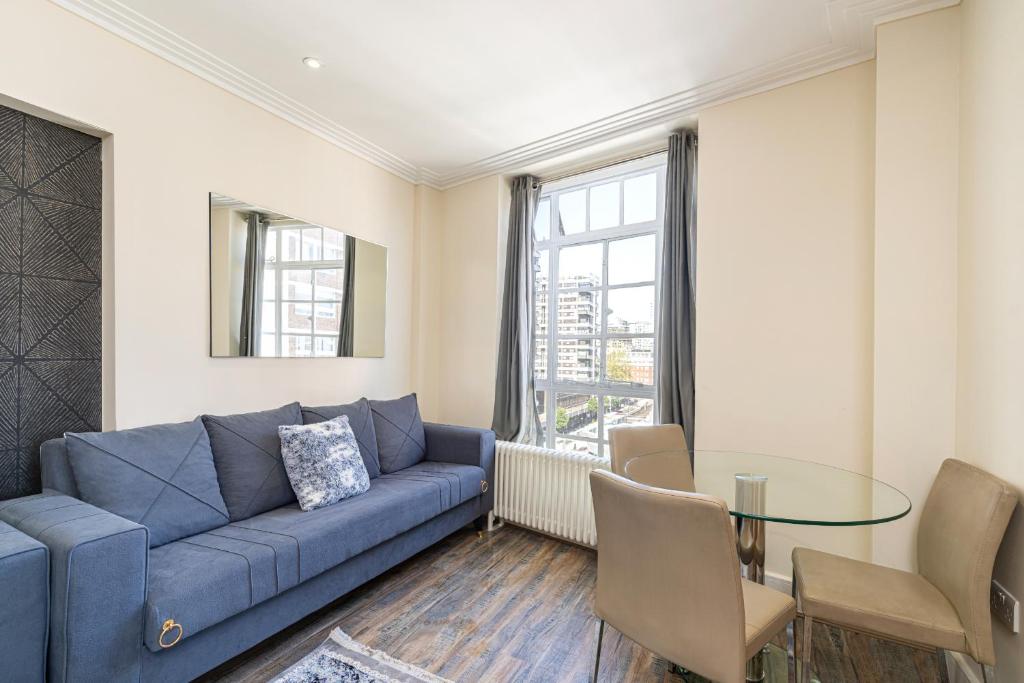 a living room with a blue couch and a glass table at Hyde Park Apartments in London