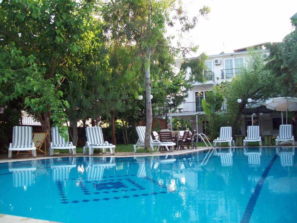 a swimming pool with white chairs and a fountain at Hotel Vanilla in Fethiye