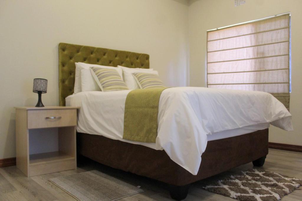 Staybridge Golfview Suites في غابورون: غرفة نوم بسرير كبير وموقف ليلي