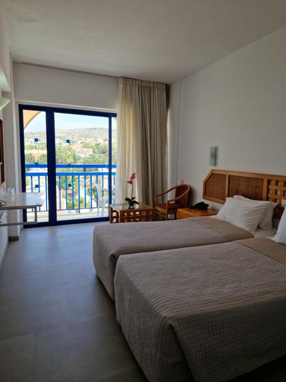 リマソールにあるNavarria Blue Hotelのベッド2台とバルコニーが備わるホテルルームです。