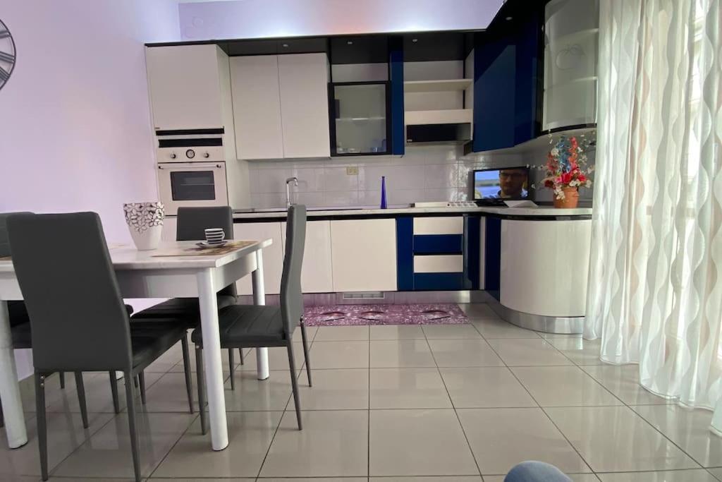 een keuken met blauwe en witte kasten en een tafel en stoelen bij Casa vacanze “Villa Paola” in Pescara