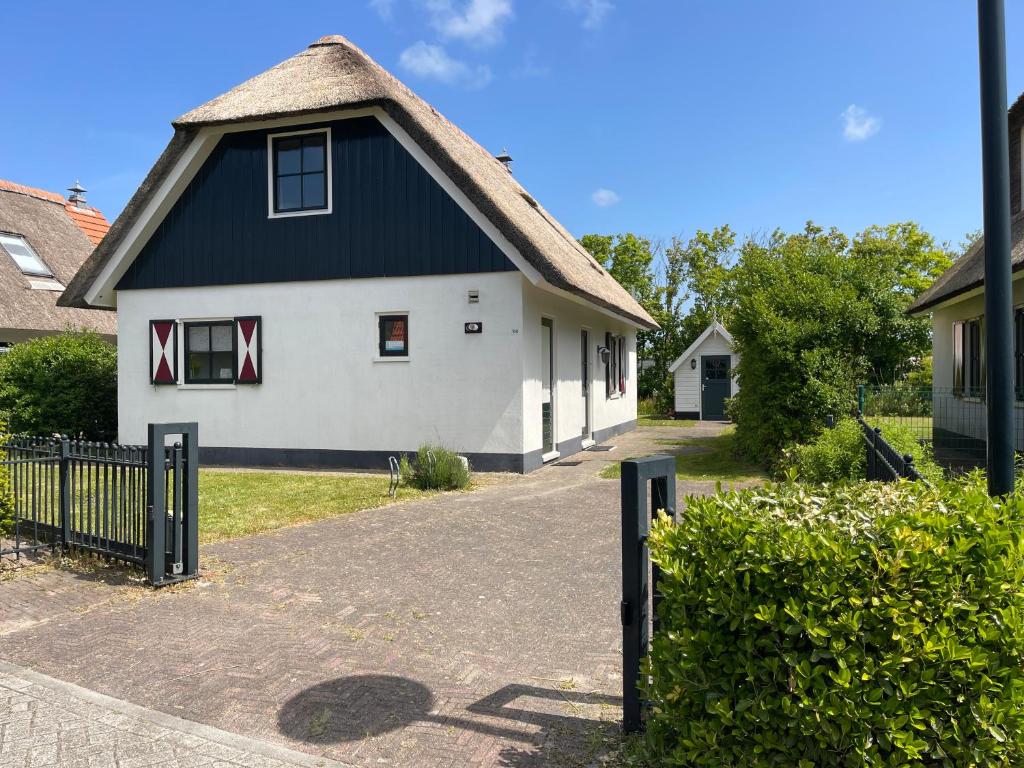 a white and black house with a black roof at Villa Buiten 108 in Callantsoog