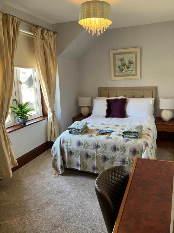 1 dormitorio con cama, mesa y lámpara de araña en Advie Lodge, en Inverness
