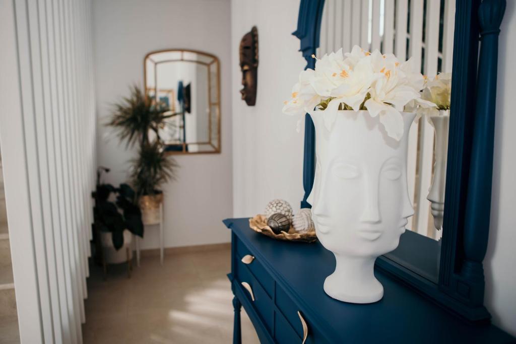 Flowers & Faces Guesthouse في بونتي دي ليما: خزانة ملابس زرقاء مع مزهرية بيضاء مع الزهور فيها