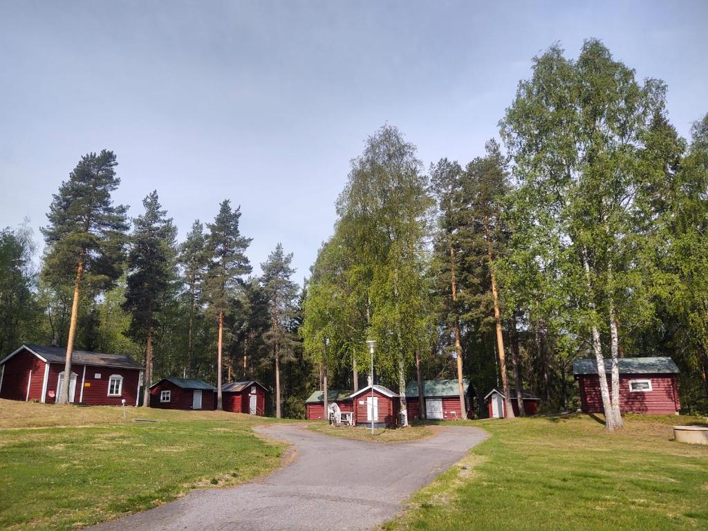 a group of red cabins in a field with a road at Selholmens Camping in Älvsbyn