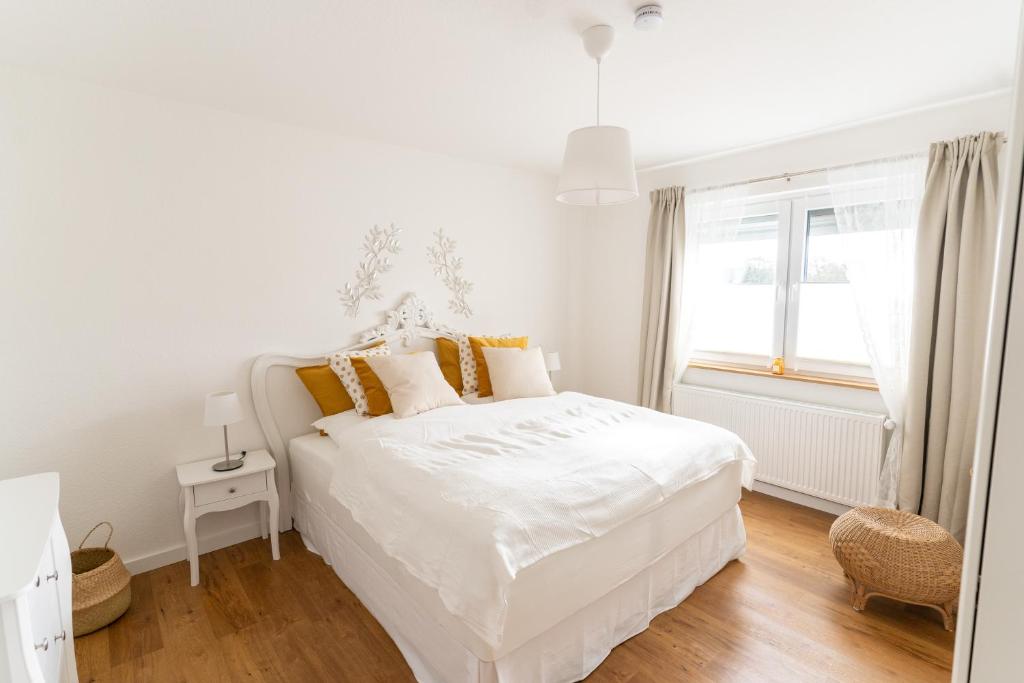 a white bedroom with a white bed and a window at Ferienwohnung Gartenkamp Celle in Celle