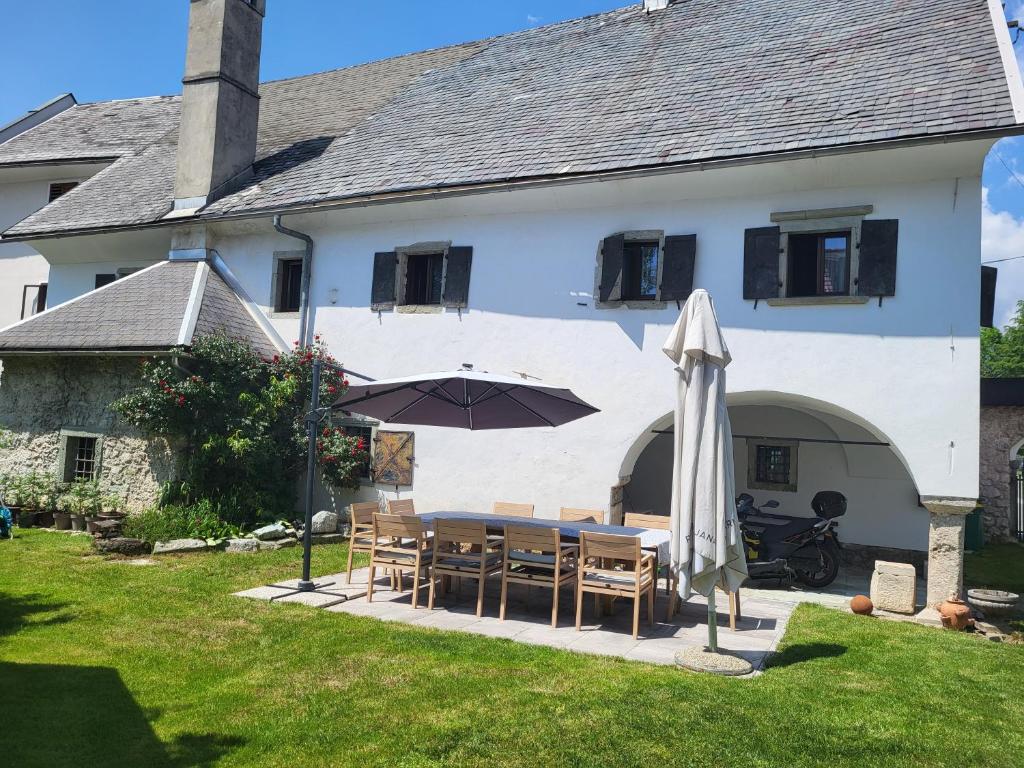 ein Haus mit einem Tisch und einem Sonnenschirm im Hof in der Unterkunft Baroque villa near Bled - Resort Vidmar in Lesce