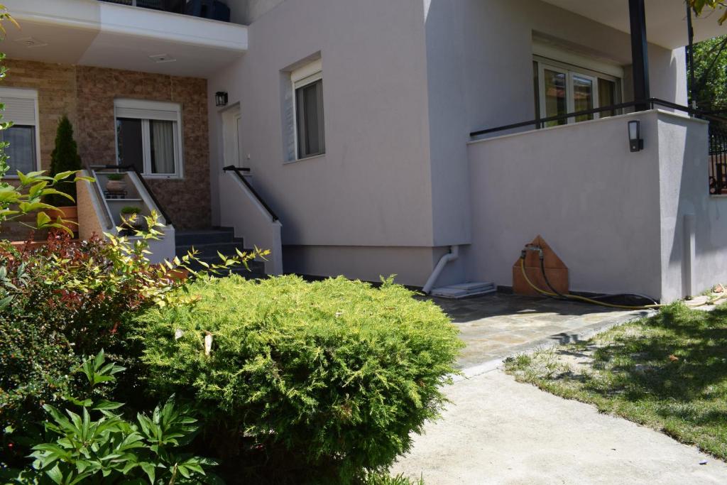 une maison avec une terrasse couverte et quelques buissons dans l'établissement Nakis Apartment All Seasons, à Stavros