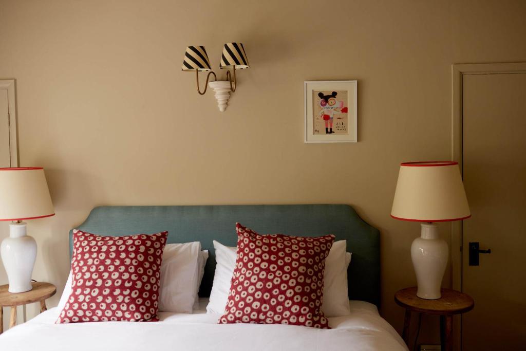 a bedroom with a bed with red pillows and two lamps at The Queen's Head in Broad Chalke
