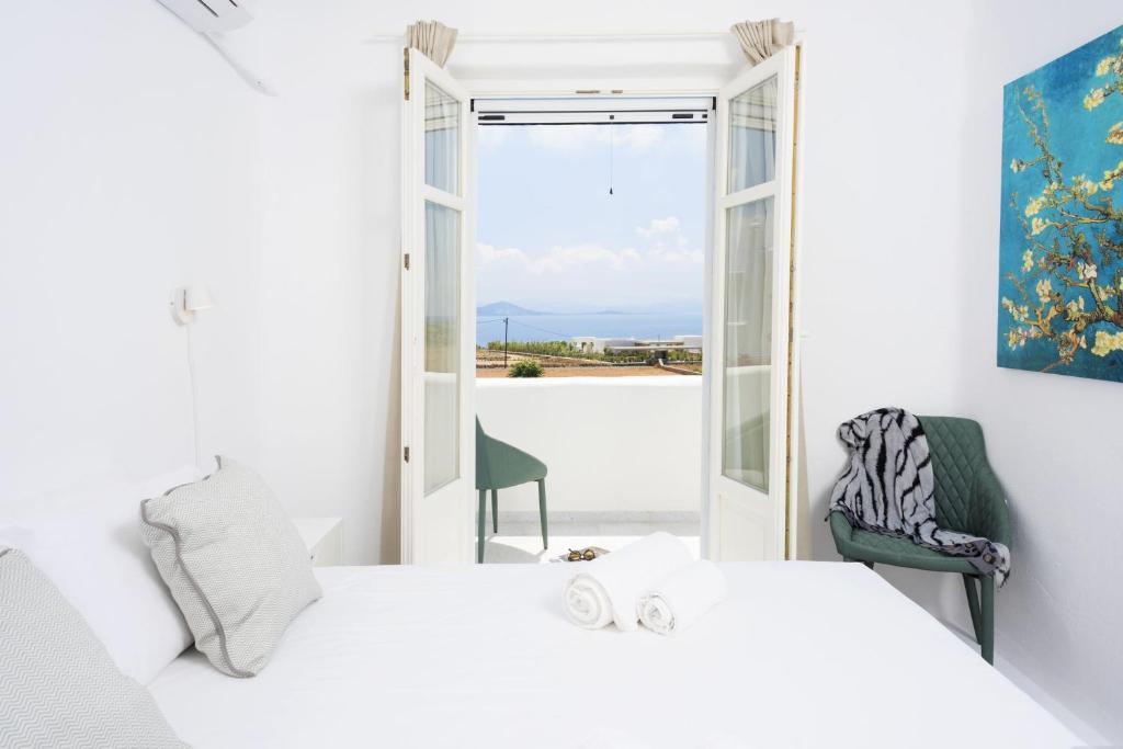 una camera con un letto e una sedia e una finestra di Seaside Paros Ampelas ad Ambelás