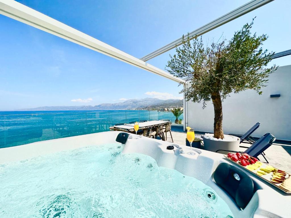 a jacuzzi tub with a view of the ocean at Skipper Beachfront Suites in Hersonissos