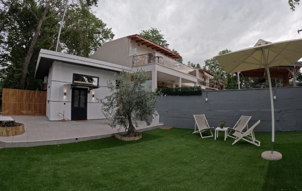 a house with a yard with chairs and an umbrella at Elia Studio in Platamonas