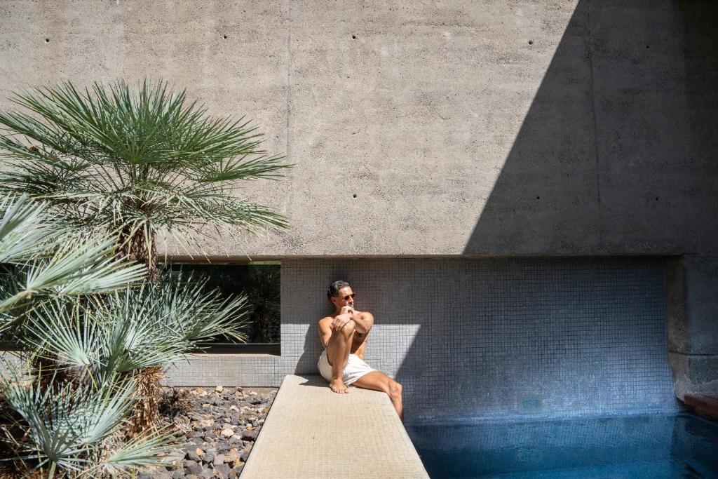 a man sitting on a bench next to a pool at Iberostar Heritage Grand Mencey in Santa Cruz de Tenerife