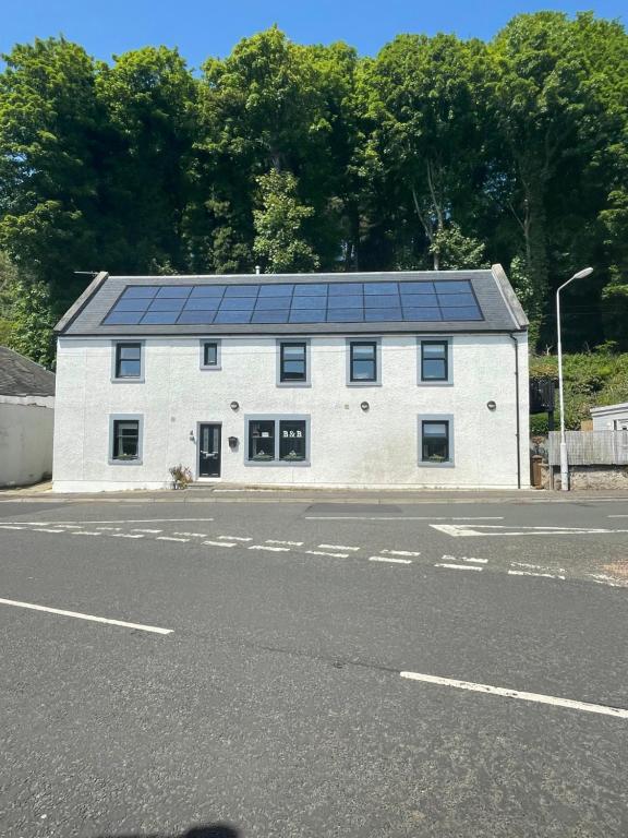 un bâtiment blanc avec des panneaux solaires en haut dans l'établissement Saorsa House Culross, à Fife