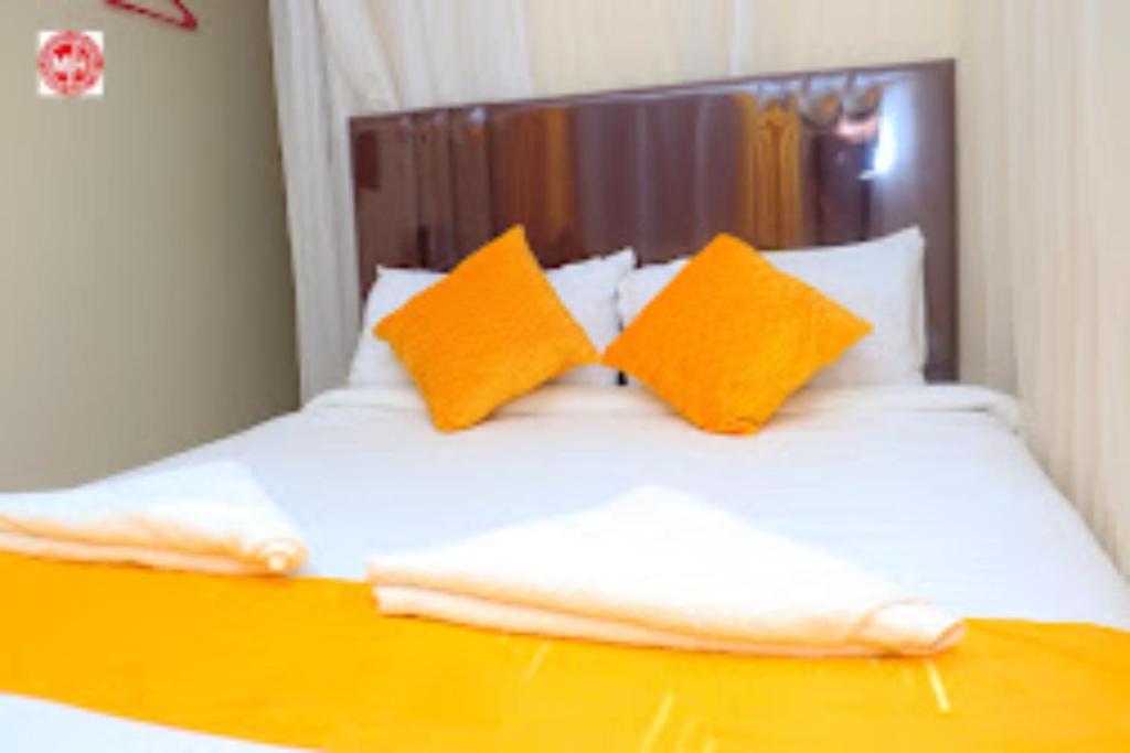 Una cama con almohadas naranjas y blancas. en Machakos Inn Hotel, en Machakos