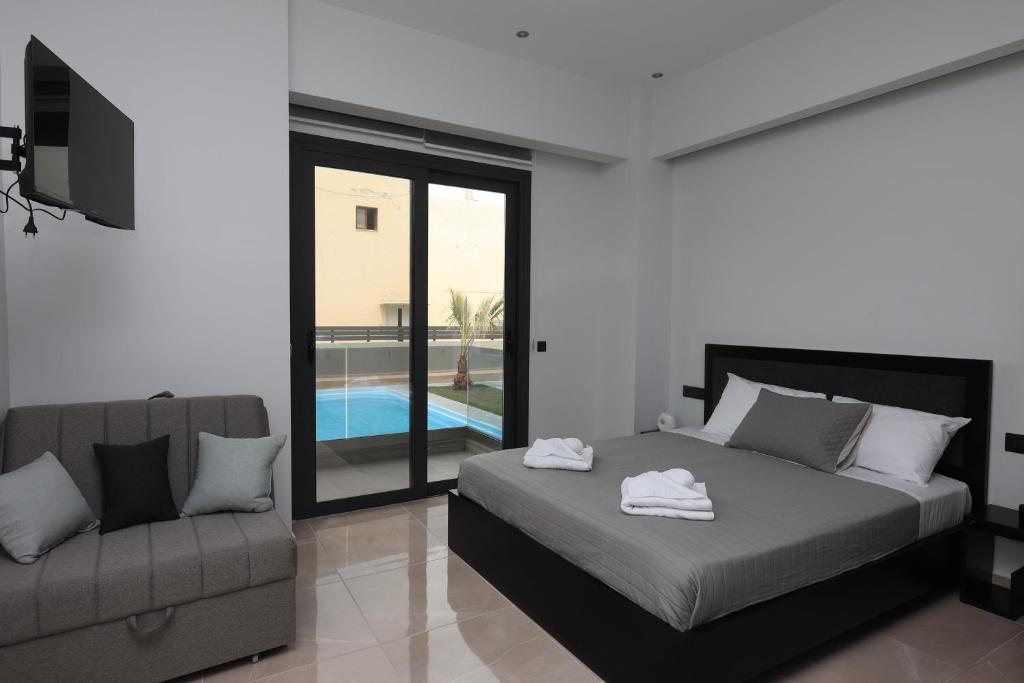 a bedroom with a bed and a couch and a pool at Luana Monte Apartments in Amoudara Herakliou