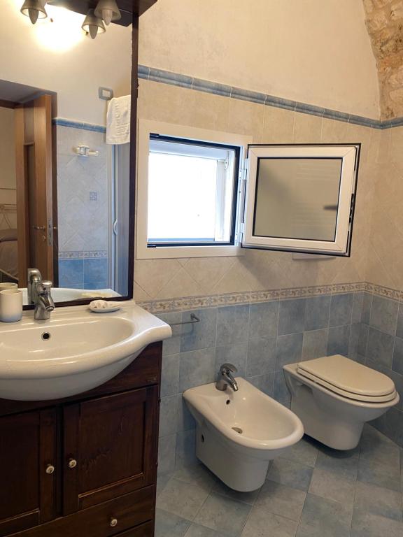 a bathroom with a sink and a toilet and a mirror at Nonno Pasquale house in Locorotondo