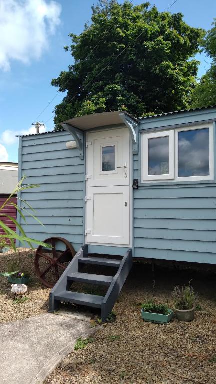 einem blauen Wohnwagen mit einer weißen Tür und einer Treppe in der Unterkunft Bramblewick House in Longford