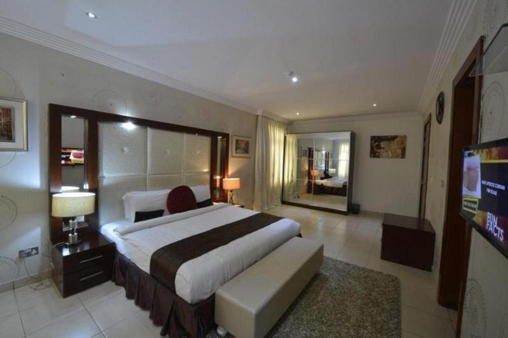 Palazzo Dumont Hotel في Ikuata: غرفة نوم كبيرة بسرير كبير وتلفزيون