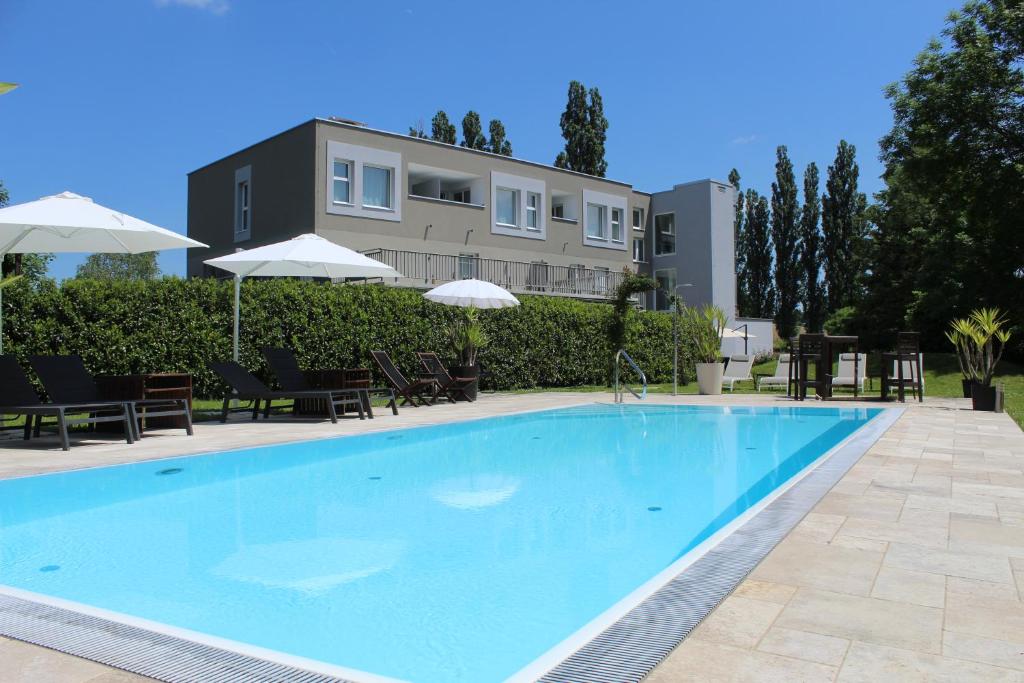 a swimming pool with chairs and umbrellas in front of a building at Ewitsch 13 - Hotel Garni in Berghausen