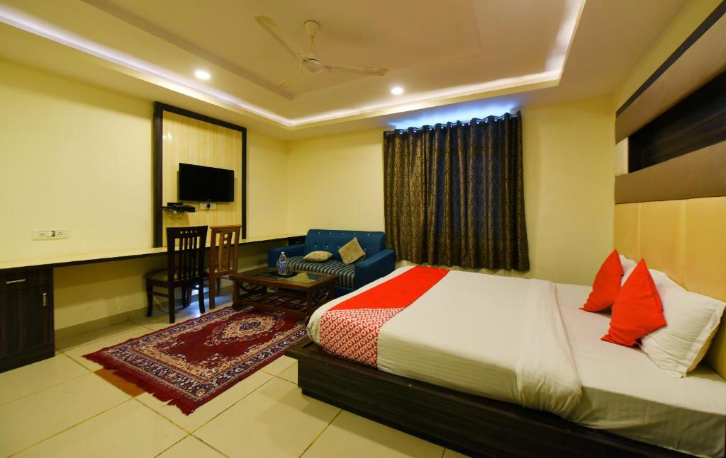a bedroom with a bed and a couch and a television at Collection O Tip Top in Jaipur