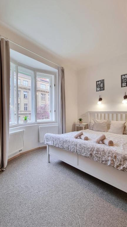 a white bedroom with a large bed and a window at Finnem Rentals Zíkova in Prague