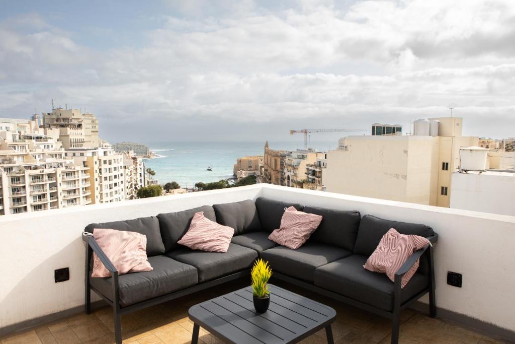 un sofá en un balcón con vistas al océano en Entire Luxury Sliema Townhouse Steps from Beach en Sliema