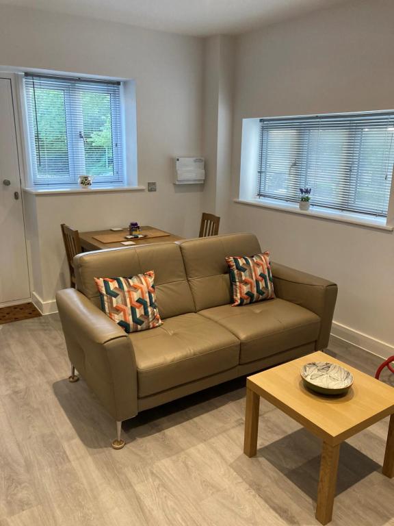 a living room with a brown couch and a table at Dartmoor View one bedroom Apartment Dog Friendly Close To Town FREE PARKING in Totnes