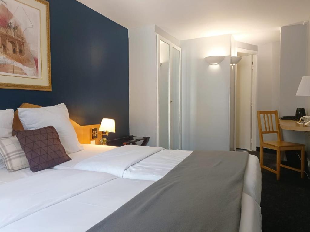 Un dormitorio con una gran cama blanca y una mesa en Grand Hotel Du Calvados, en París