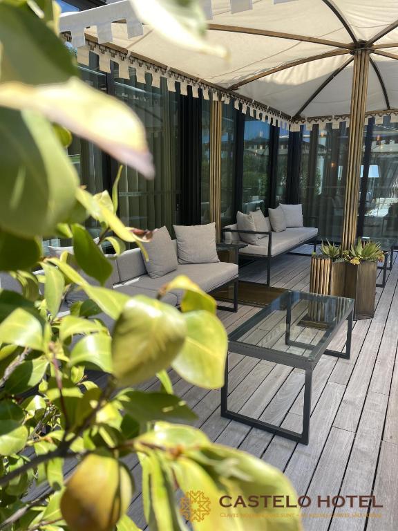 un patio con sofás y una sombrilla en un edificio en Castelo Hotel, en Chaves