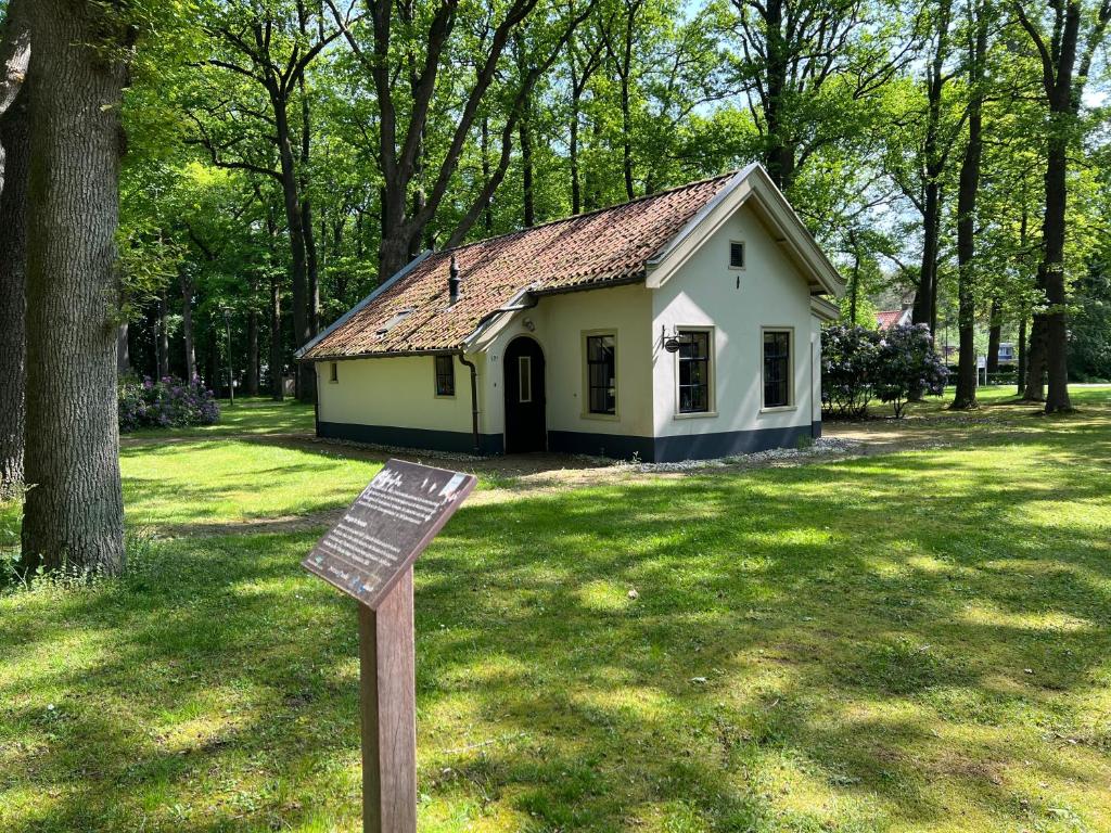 een klein huis met een bord in het gras bij De Consistorie in Veenhuizen
