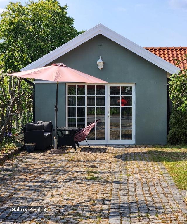 ein Haus mit einer Terrasse mit einem Sonnenschirm und einem Tisch in der Unterkunft ÖSTERLEN PARKEN in Simrishamn