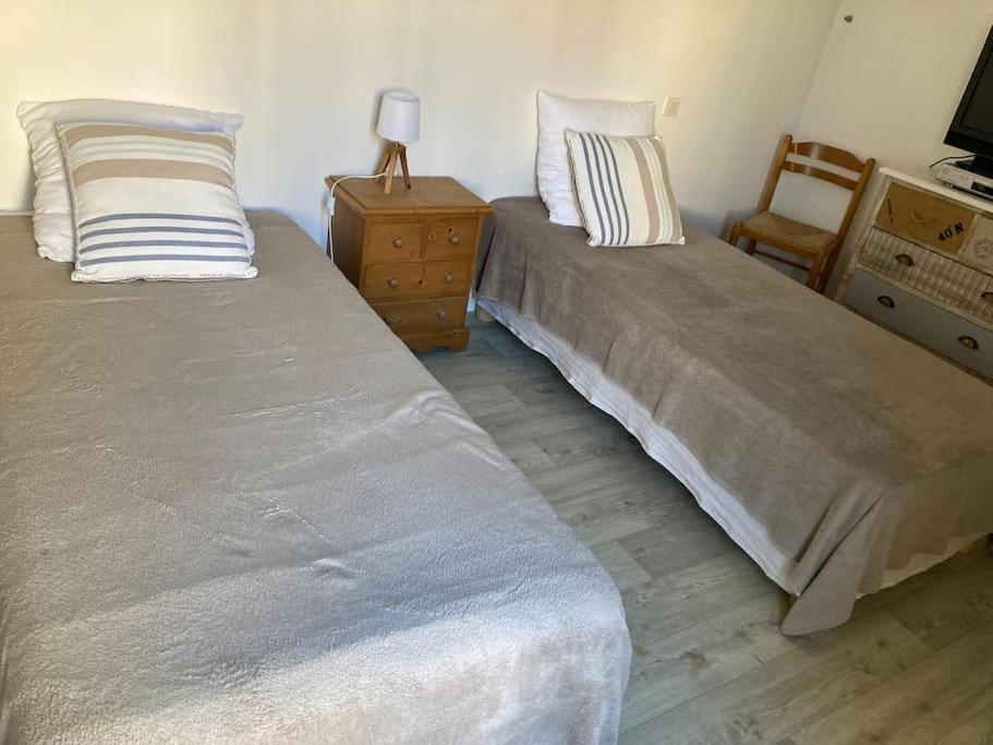 two beds in a room with a chair and a table at Appart Hypercentre Biarritz - PKG &#47; WIFI &#47; 4-6 Personnes in Biarritz