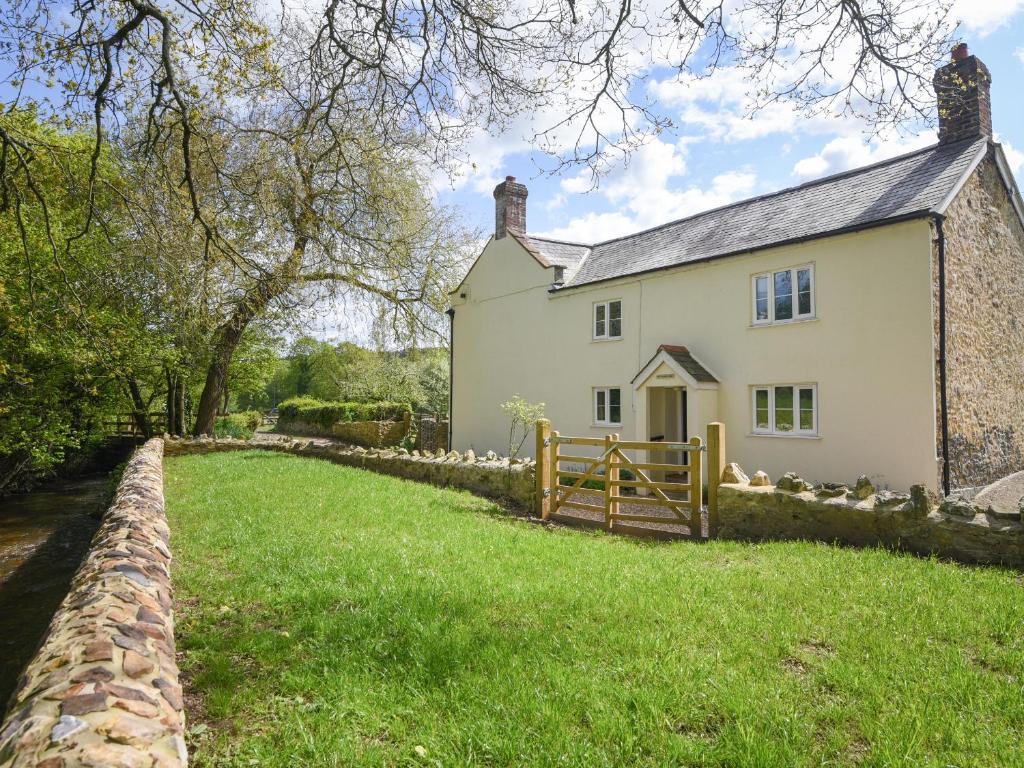 a white house with a fence and a grass yard at Riverbank in Axminster