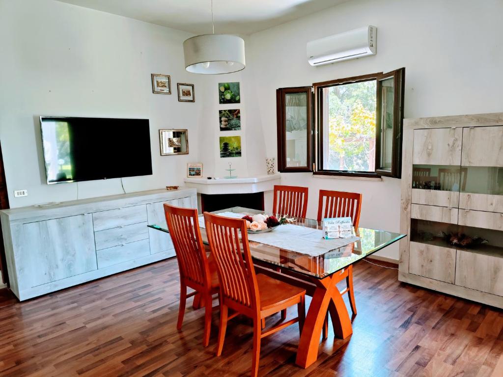 ein Esszimmer mit einem Tisch, Stühlen und einem TV in der Unterkunft Villa Raffaella in Lecce