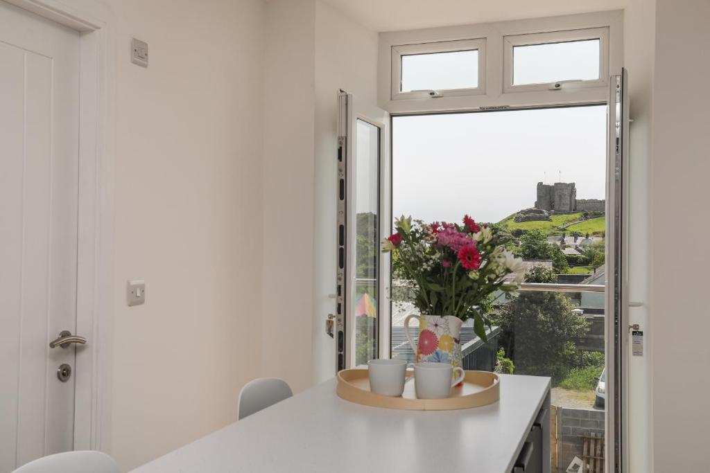 kuchnia z oknem i stołem z kubkami i kwiatami w obiekcie Swn Y Mor Sound of the Sea w mieście Criccieth