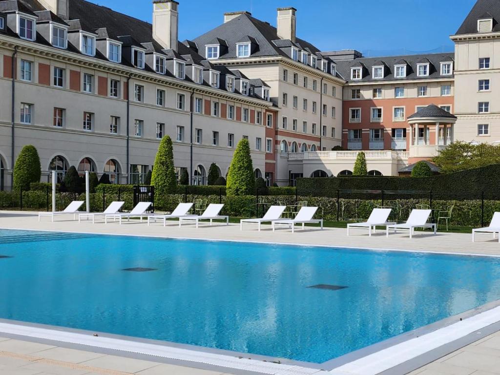 basen przed budynkiem z białymi leżakami w obiekcie Dream Castle Hotel Marne La Vallee w mieście Magny-le-Hongre
