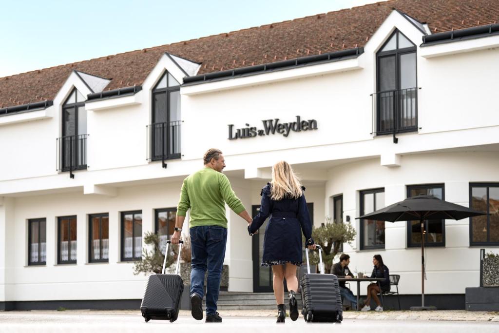 un homme et une femme marchant devant un hôtel avec des bagages dans l'établissement Luis von Weyden, à Weiden am See