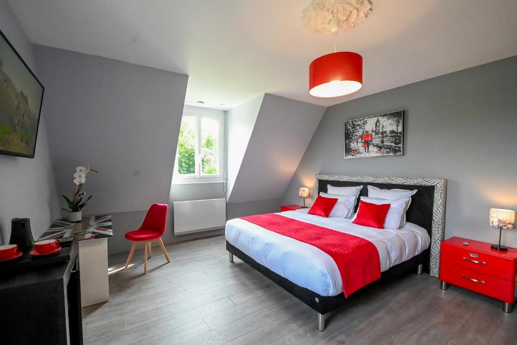 a bedroom with a large bed with red pillows at La Fontaine Dort in Tessy-sur-Vire