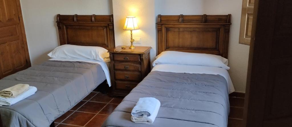 Un dormitorio con dos camas y una lámpara sobre una mesa. en Albergue el Caseron de Fuentes Carrionas, en Cardaño de Abajo