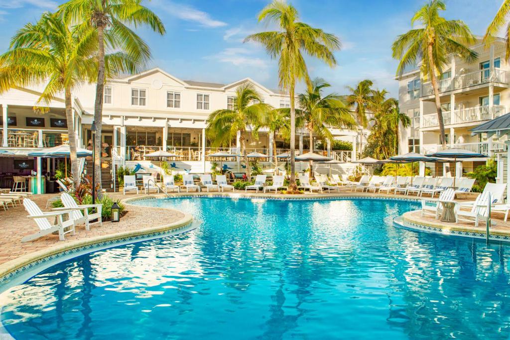 キーウェストにあるMargaritaville Beach House Key Westのリゾート内のヤシの木と椅子付きのスイミングプール